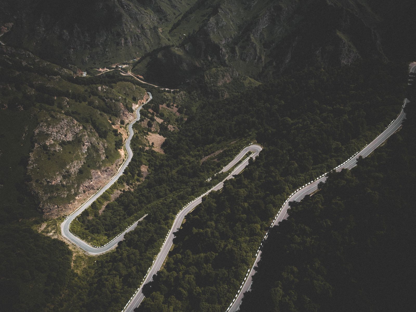 Aerial view of a mountain road curving through forest.