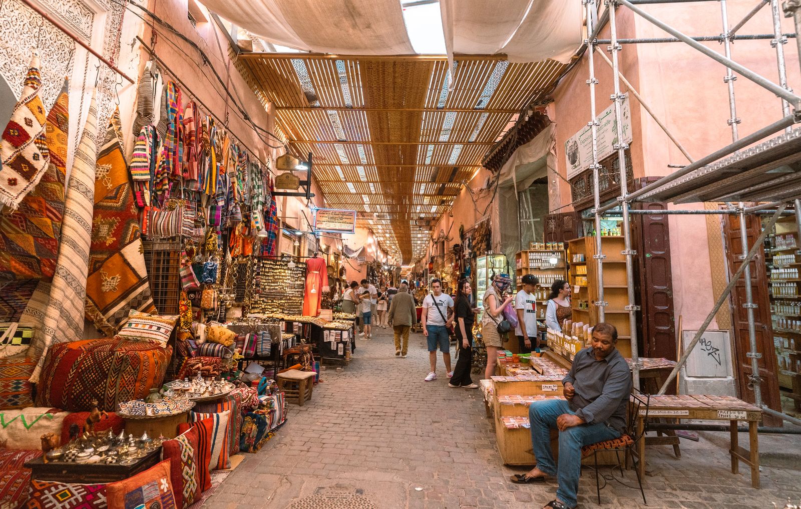 A crowded souk alley hung with fabrics and lanterns.