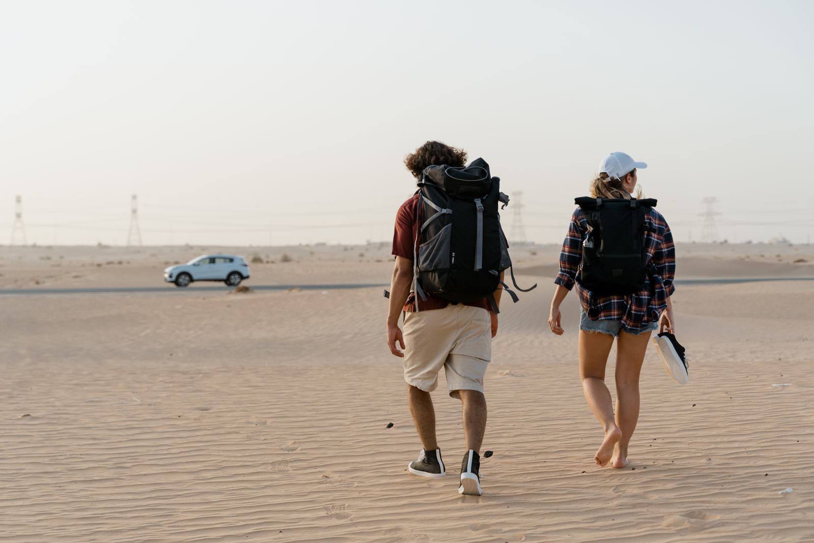 Two hikers with backpacks walking into a vast desert.