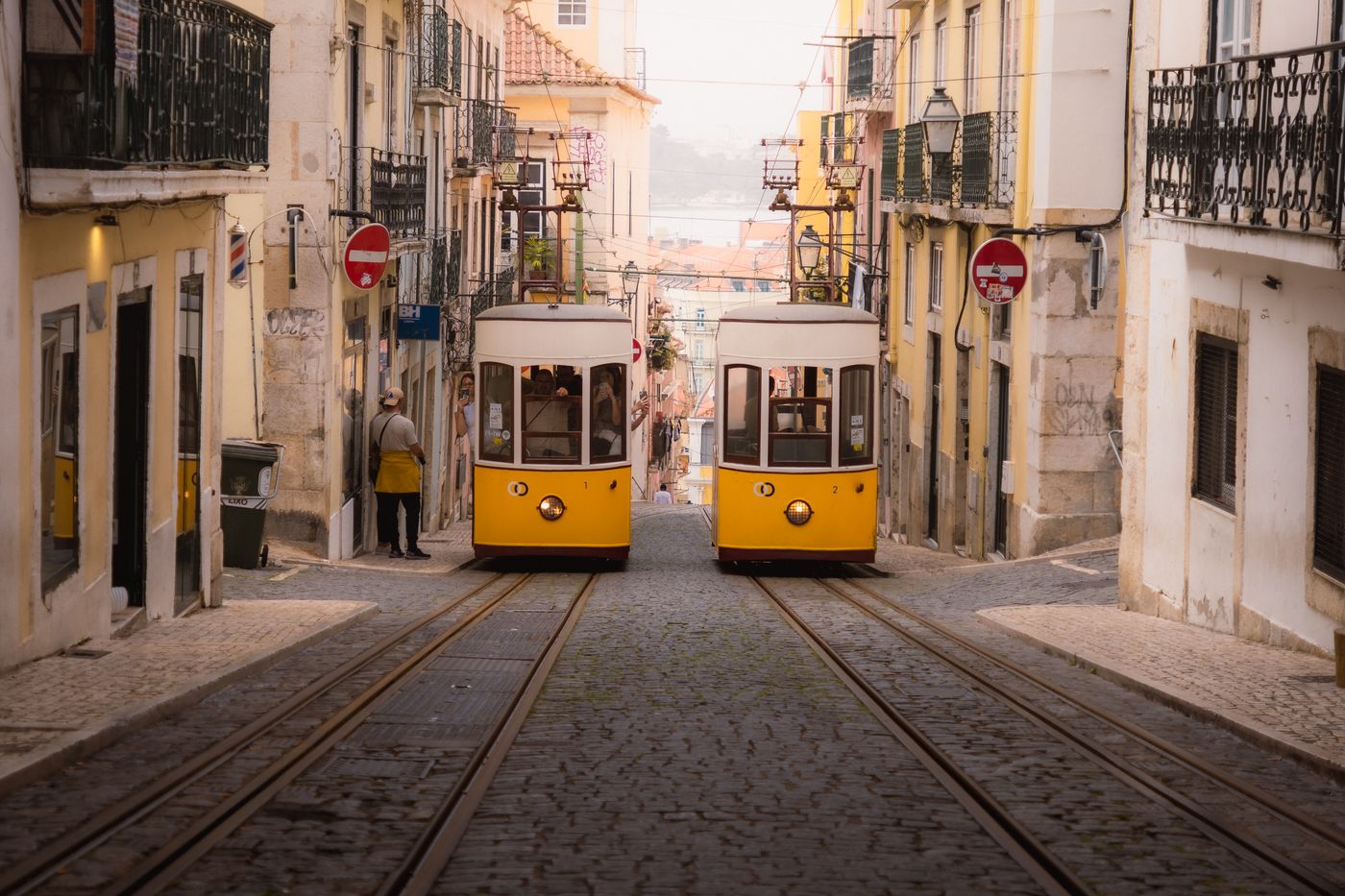Yellow trams on a cobbled street in Lisbon's old town.