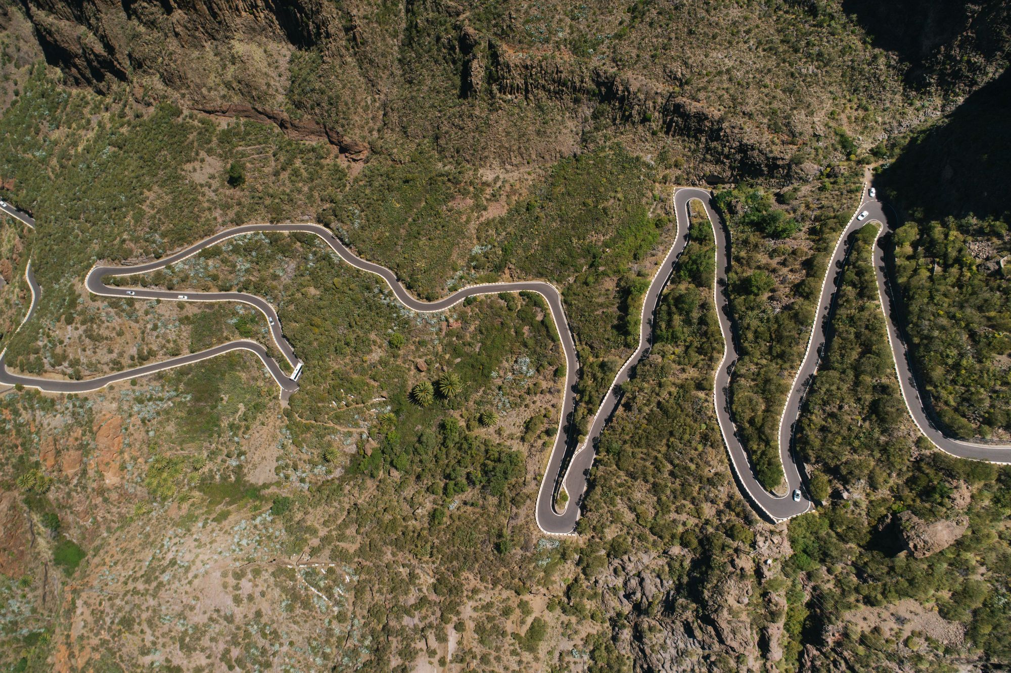 Aerial view of a mountain road winding through green hills.